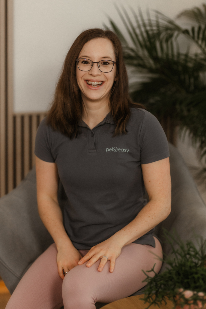 großes Portrait von Carina Gerlach auf dem Sessel sitzend mit Pflanze im Hintergrund